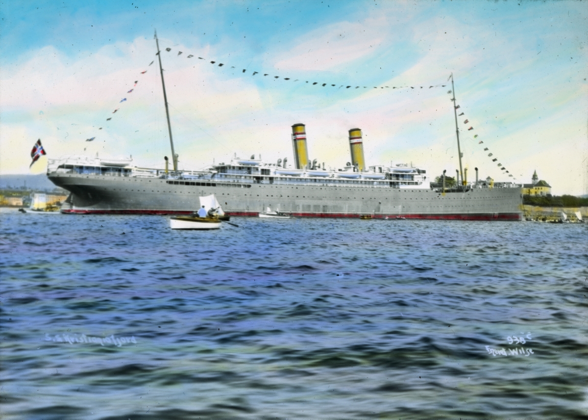 Håndkolorert dias. Passasjerskipet "Kristianiafjord" utenfor Akershus festning. "Kristianiafjord" var Den Norske Amerikalinjes første flaggskip. Skipet var på 10 000 bruttotonn og ble sjøsatt i 1913.