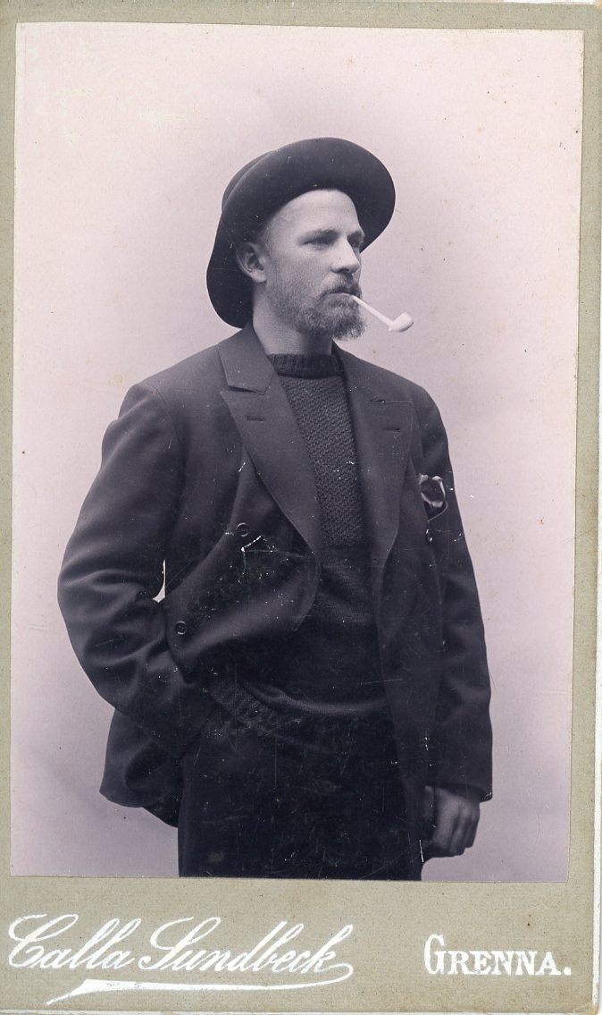 Kabinettsfotografi av en man med hatt och kritpipa i munnen.