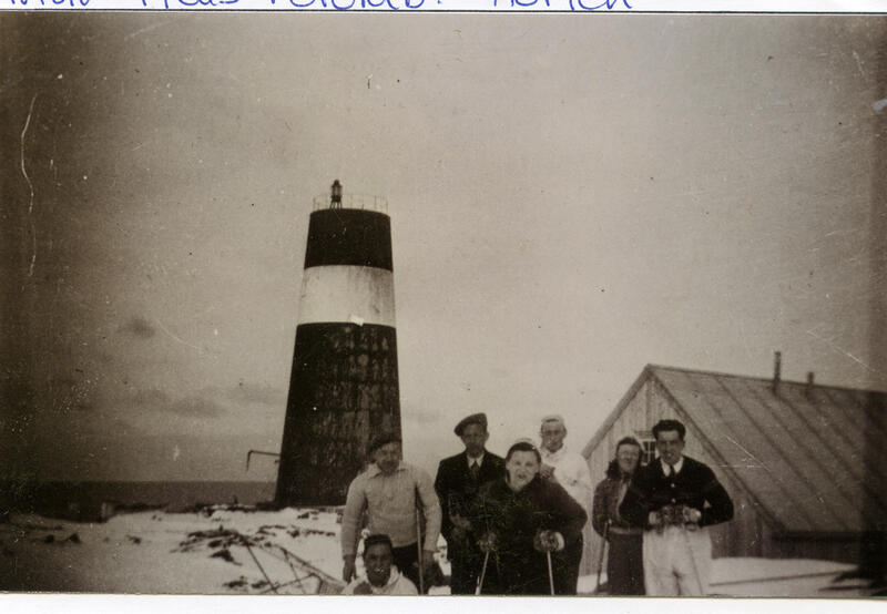 Et sort-hvitt bilde av en gruppe mennesker foran Slettnes fyr. Fyret som vises er lavere enn dagens fyr.