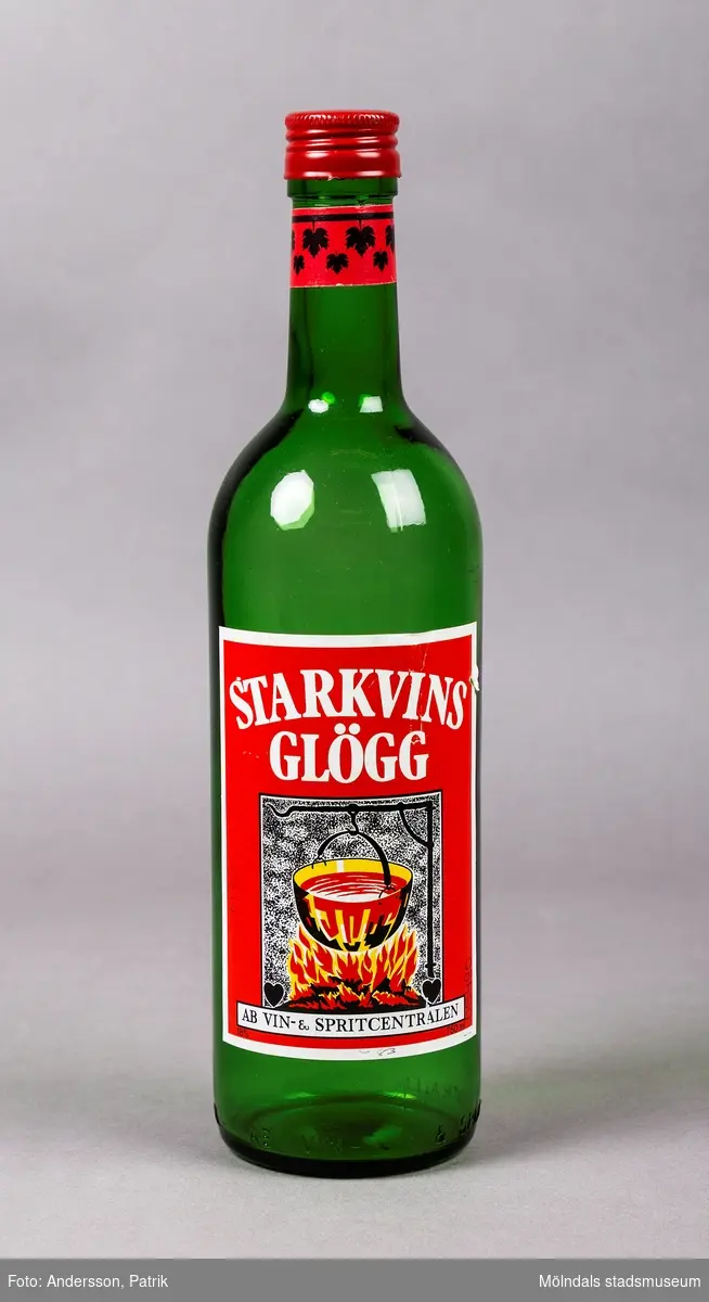 En grön glasflaska som tidigare innehållit glögg. Flaskan som har formen av en vinflaska har en stor röd och vit etikett på framsidan. På etiketten finns en bild av en brinnande eld med en gryta som hänger ovanför. Grytan innehåller vätska som förmodligen föreställer glögg. Flaskan har ett rött skruvlock. Under locket finns en liten röd manchett med bladmotiv i stiliserad form.
Flaskan är från tiden efter 1989, men innan Blossa tog över Vin & Spritcentralens sortiment.