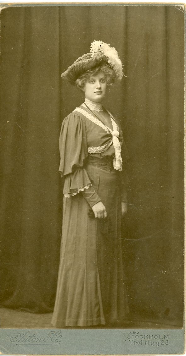 Kabinettsfotografi av en okänd ung kvinna i helfigur med plymhatt.