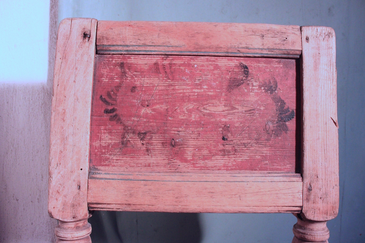 Stol av trä. Fyra svarvade ben med tvärslåar. Ryggstödet är två svarvade stolpar med en hel infälld träplatta. Framsidan  målad i rött med svart dekormålning. Baksidan skrivet datum, 1801, inramat med lodräta sträck och liggande S i turkos eller blått.