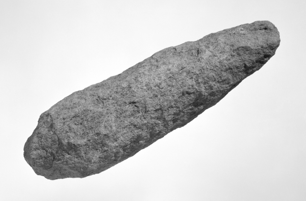 Emne til trinnøks fra mesolitikum. Formen er tilhugget til en spissnakket trinnøks, men ingen sliping eller finere prikkhugging er foretatt. Steinen er tung, trolig grønnlig diabas.