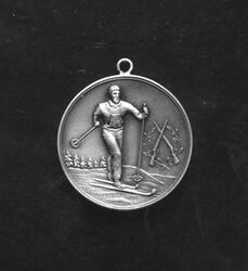Bilde av en medalje som har bilde av en skiløper i fullt sprang