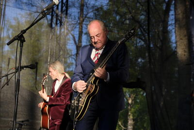 Eldar Vågan spiller innbitt på elgitar under sin konsert i parken ved Eidsvollsbygningen 17.mai 2022, i bakgrunn med kassegitar ser vi Jon Anders Narum.