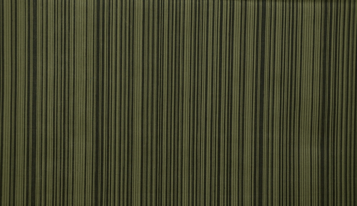 Bomullstyg, 1960-tal.
Klännigstyg på 90 cm bredd. Tryckt mönster med smala svarta ränder på mossgrön styckfärgad vara.
Rapport --x  26 cm.
Tryckfärger 1.