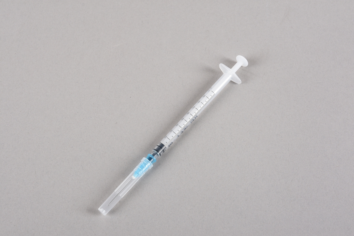 Vaksinasjonsutstyr brukt ved første vaksine mot Covid-19, satt i Bergen 05.01.2021. Utstyret består av en engangssprøyte med kanyle og beskyttelseshette og et åpnet hetteglass for Pfizer-vaksine, med tilhørende kork.