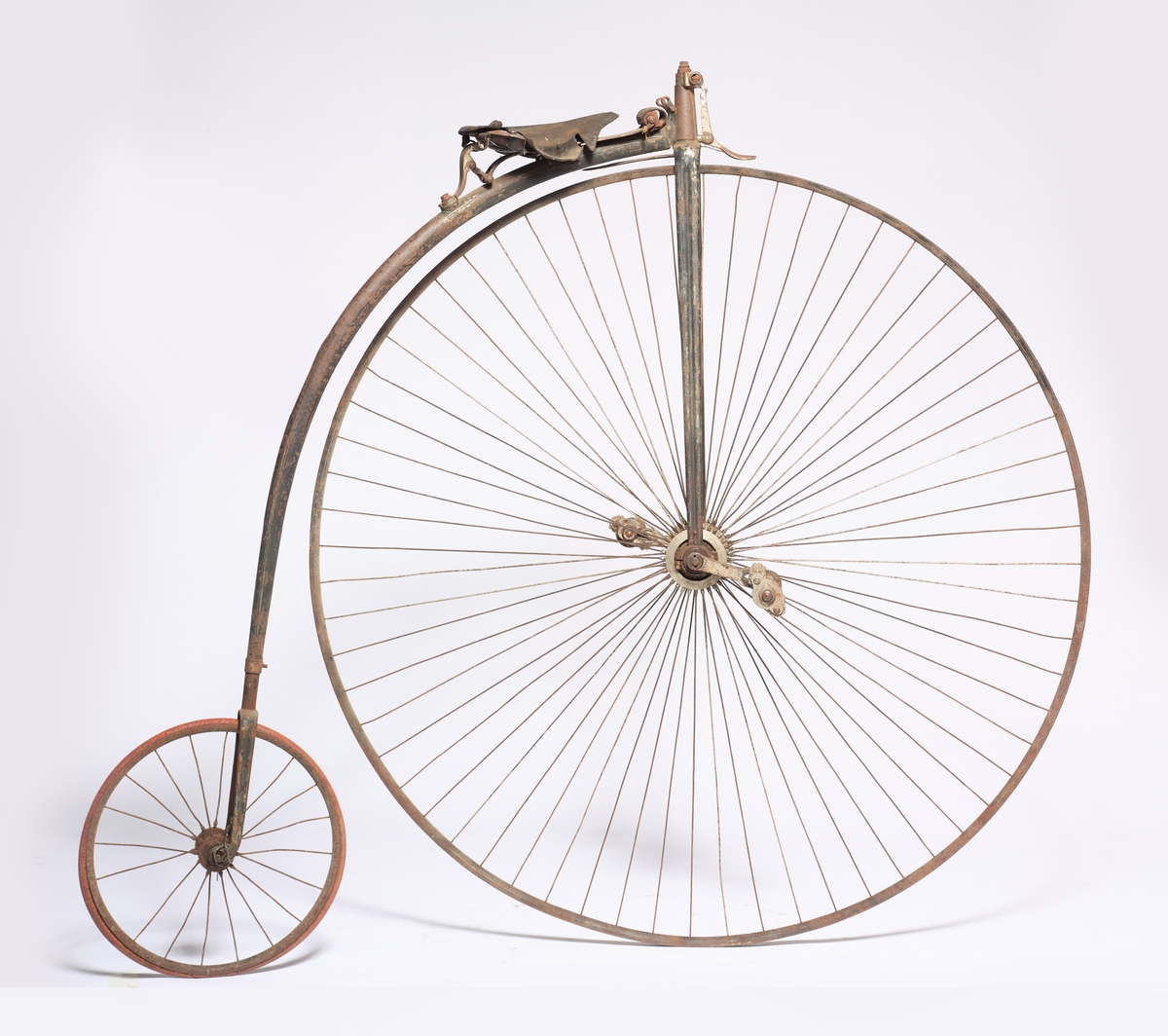 Sykkelen har ett stort og ett lite hjul. Halve styret er en del av bremsen, gummiringen på det store hjulet mangler. Den har vært svartmalt med hvite striper, og er produsert i England.