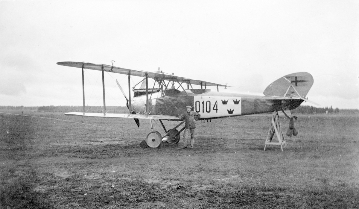 En civilklädd man står framför flygplan FVM S 18, nummer 0104 omkring 1920-1922.