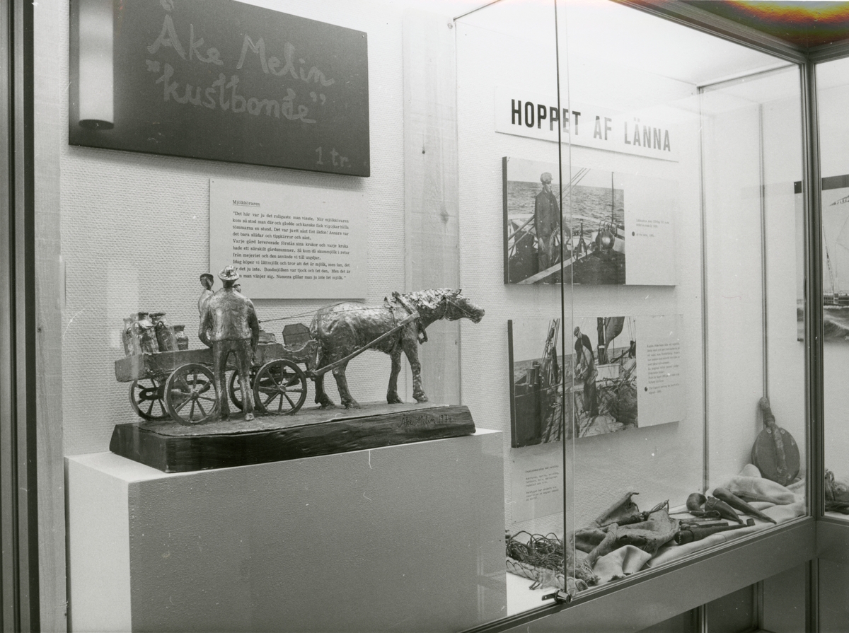 Utställningen "Småbrukarliv i kustbyggd – Åke Melin". Pesentation av utställningen i trappmonter med bla en skulptur föreställande en kustbonde och hans djur.