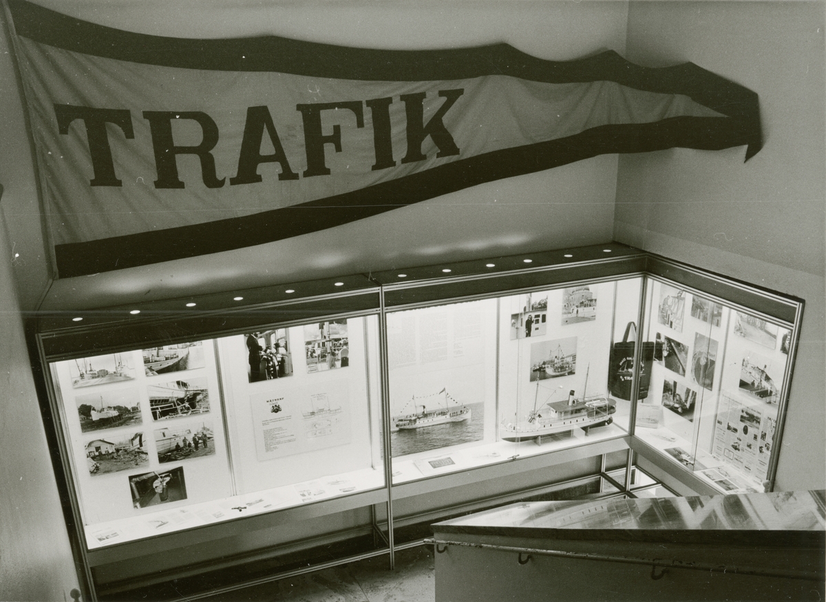 Utställningen "SS Trafik". Överblick av utställningen i trappmontern. Fotografier, vimpel och fartygsmodell kopplade till SS Trafik.