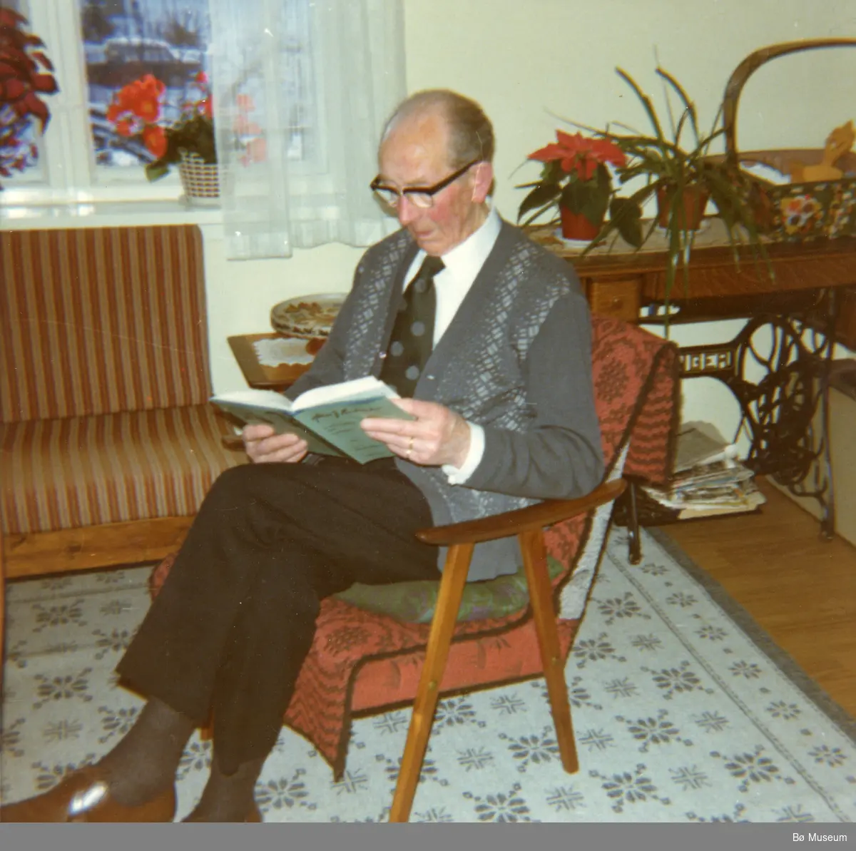 Halvor Storhaug sit og les i lenestol, nyttårsaften 1977