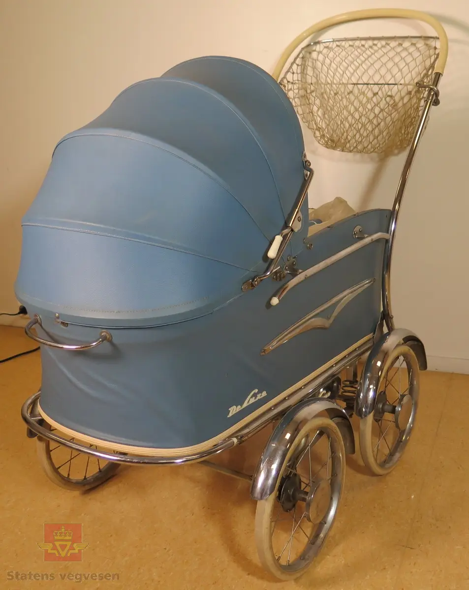 Barnevogn, 2-akslet med totalt fire hjul. Hjulene har kompaktgummi. Vogna er blå med hvite og forniklede detaljer. Trekk, madrass og dyne føger med.