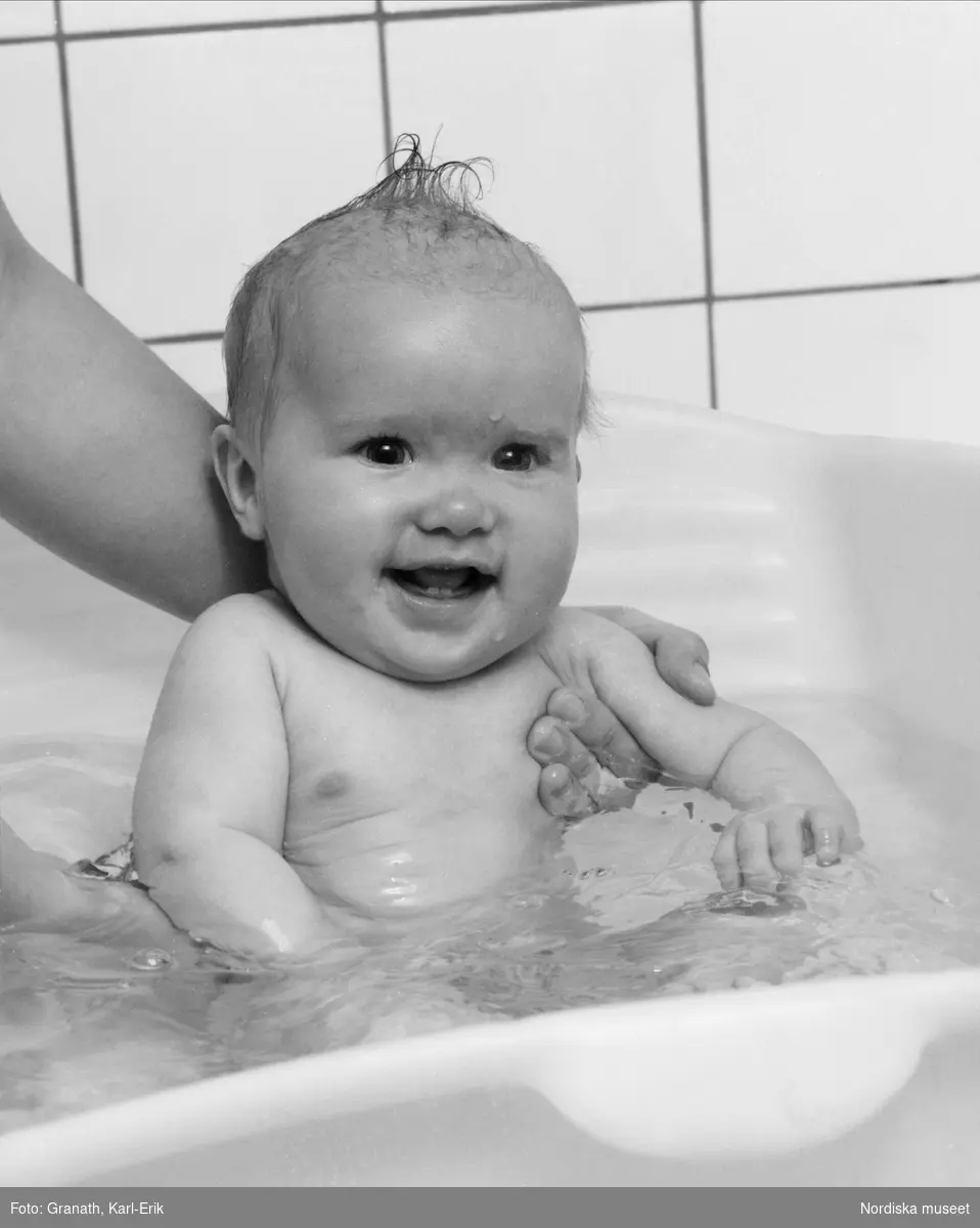 Ett spädbarn badas och tvättas i en badbalja.
