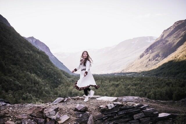 Bildet viser Kajsa Balto stående på en stein midt mellom to fjell og med utblikk over en dal. Foto: Ørjan Marekatt Bertelsen.