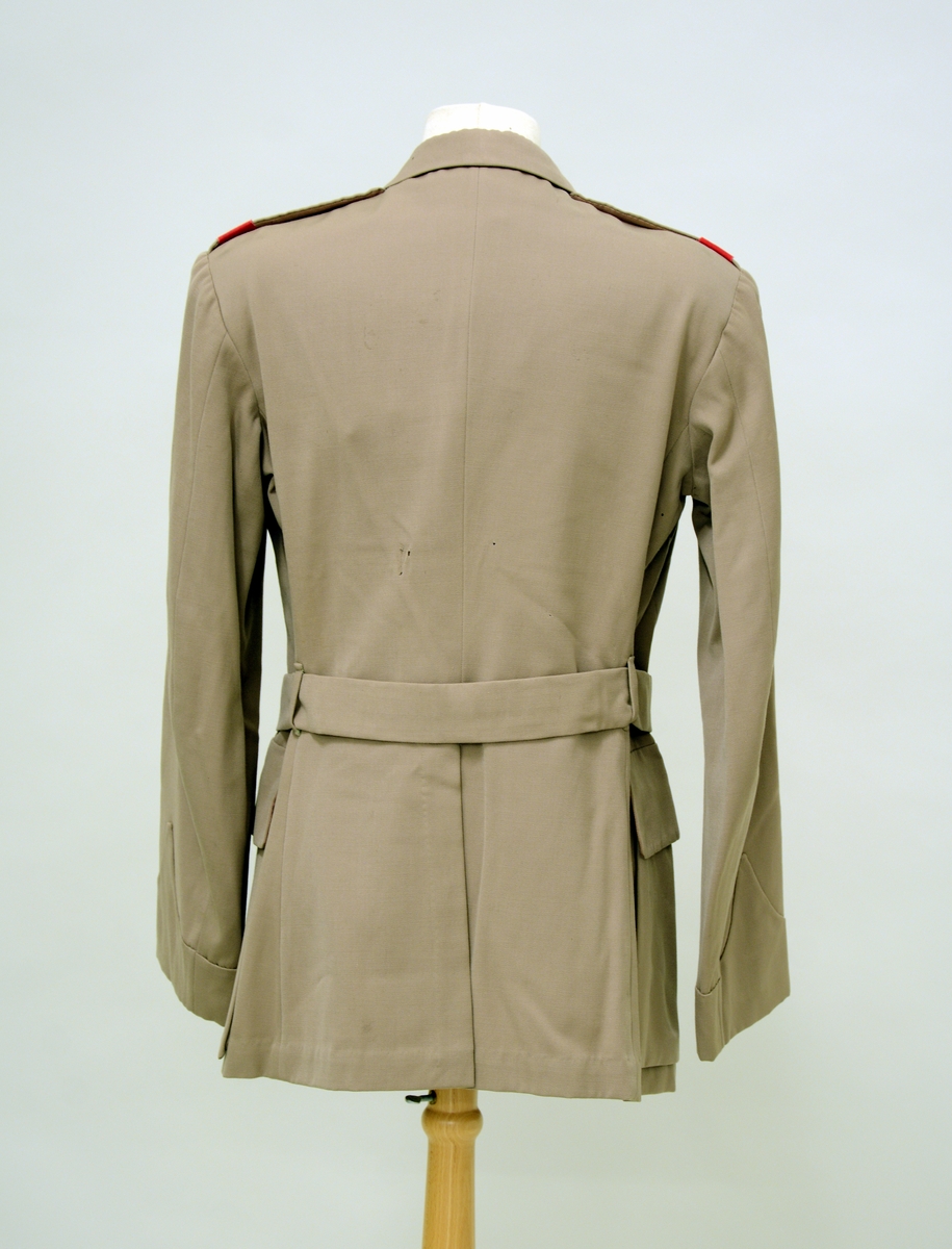 A.Uniformsjakke. Tropeuniform. Beige jakke i syntetisk materiale med 4 lommer foran. 8 knapper med emblem, skulderklaffene med rødt merke uten distinksjoner. Påsydd flygersymbolmerke foran. Jakken har fôr i armene og ved nakkepartiet. Belte med beltespenne.

B. Uniformslue. Luen har en brett festet med trykk-knapp på begge sider. Denne bretten kan brettes ut, og det blir en lue som kan festes under haken med to små knapper med emblem. Innvendig er det svettebånd og fôr.