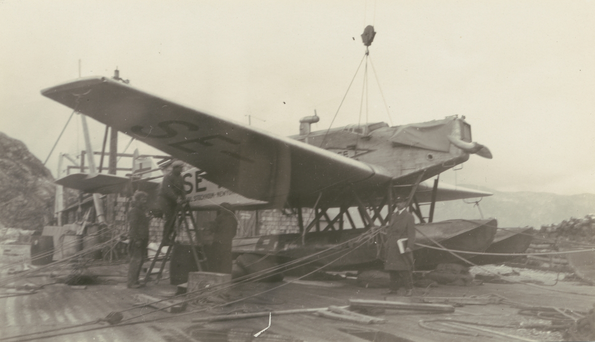 Fotografi från Albin Ahrenbergs resa till Grönland 1929. Motiv av mekaniker som inspekterar flygbåt. Fotografiet är taget i Ivigtut.