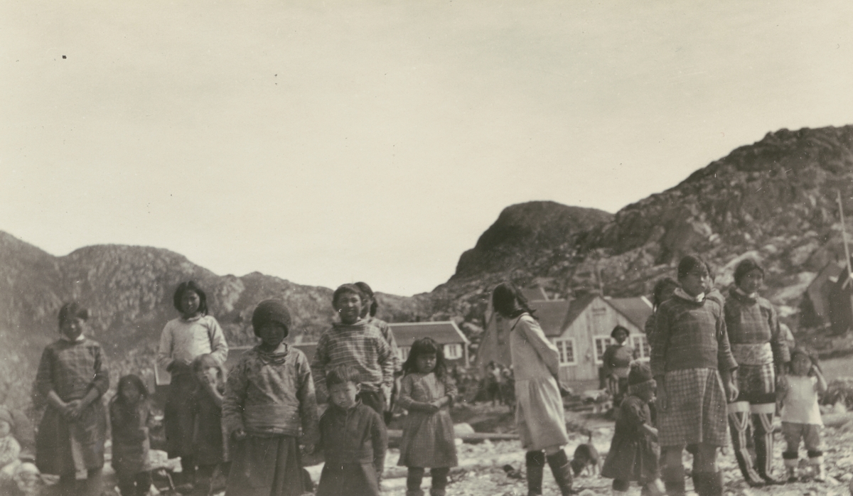 Fotografi från Albin Ahrenbergs resa till Grönland 1929. Motiv av en grupp med barn i bergslandskap på Grönland.