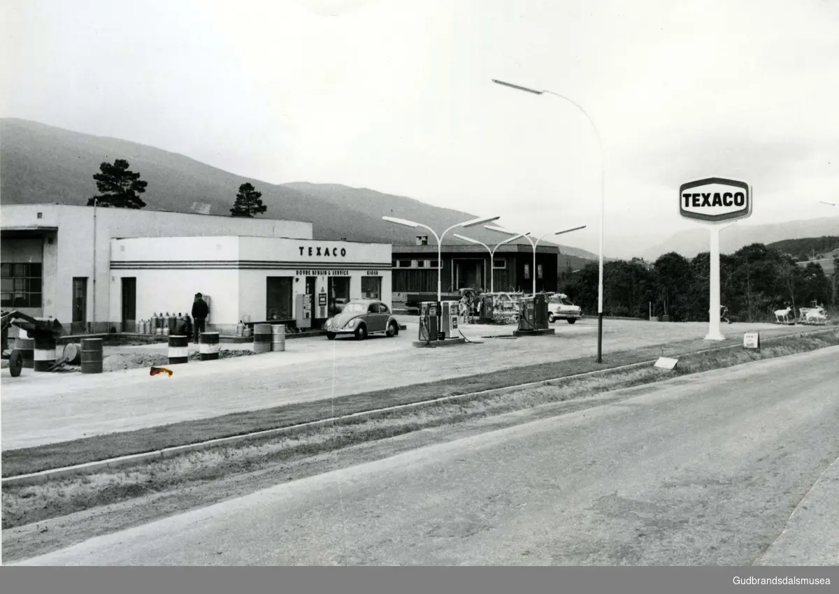 Texaco-stasjonen på Dovre rundt 1970. Arne Haugerud hadde da bygd vaske- og smøre-haller som var store nok til at vogntog kunne kjøre gjennom. E6 som går rett forbi stasjonen frmst i bildet.