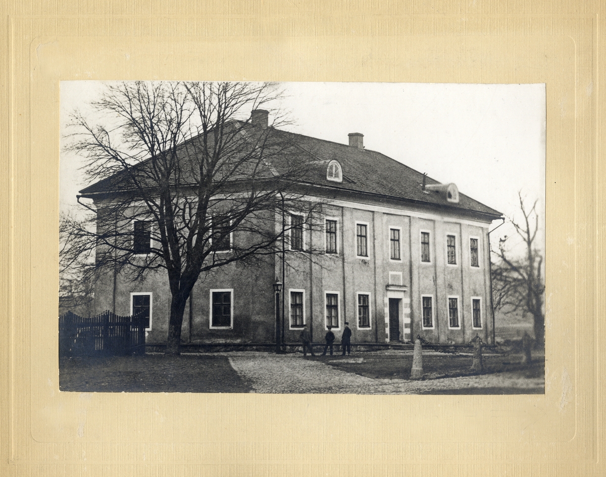 En man och två tonårspojkar står framför dåv. stifts-och landsbiblioteket, numera Karolinerhuset, 1870.