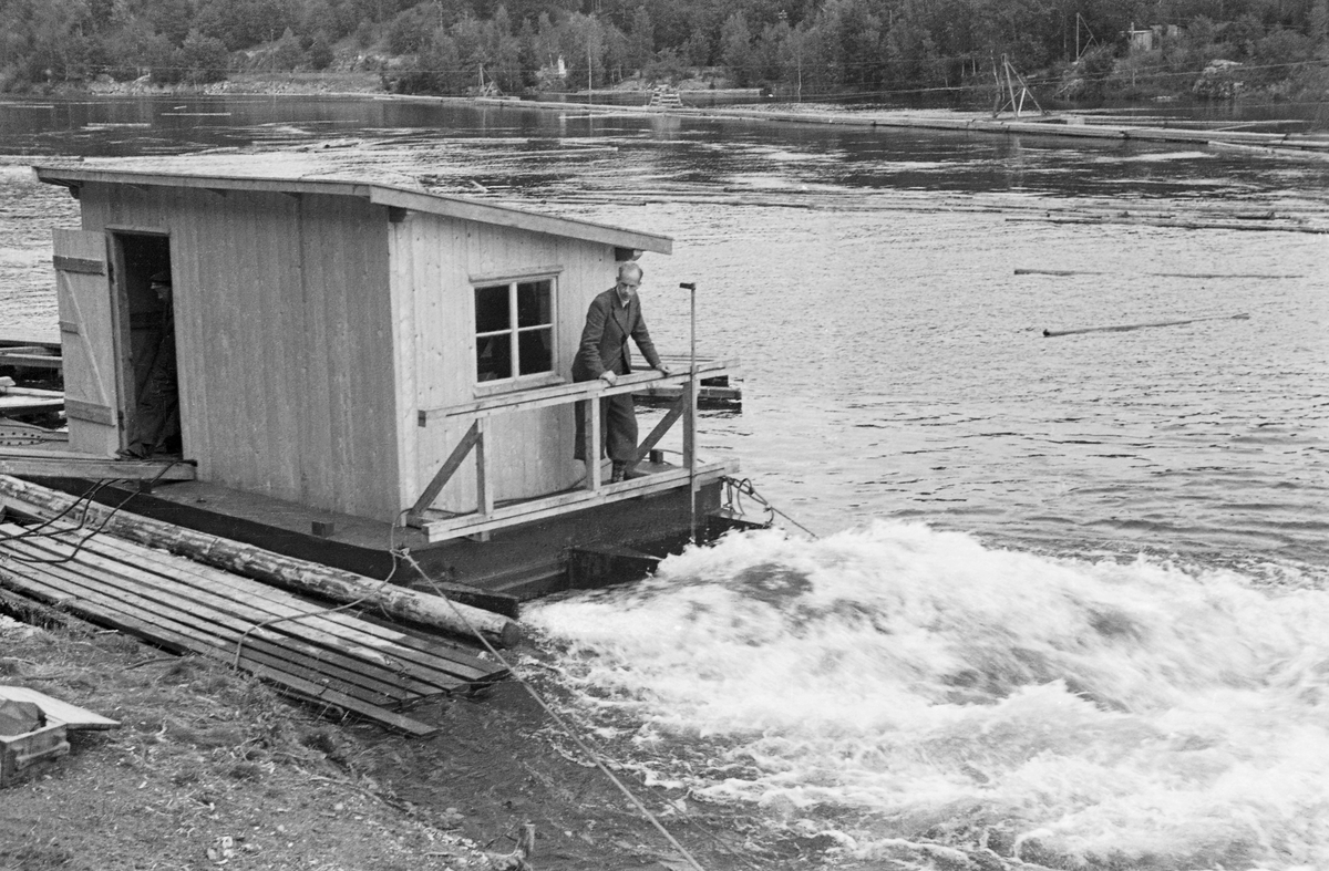 Fra forsøk med strømdannerapparat i dammen ved Kykkelsrud kraftstasjon i 1942. Da dette fotografiet ble tatt sto en mann, ingeniør Mohn, på flåten apparatet var montert på. Vannet mellom pontongene var kvitskummende og tydelig i bevegelse. Det som satte vannet i bevegelse var sannsynligvis en diger, roterende propell som befant seg i vannet, og som antakelig ble drevet av en motor som befant seg i det nevnte huset, via kjeder. Flåten ble holdt i posisjon ved hjelp av vaiere, som formodentlig var forankret i fastpunkter på land. Poenget var at propellen skulle skape en ønsket bevegelse i vannet. Her ved Kykkelsrud, hvor det var en kraftstasjon, dreide det seg antakelig om å skape strømninger som skulle bevege fløtingsvirket mot den tømmerrenna som skulle ta stokkene forbi kraftverksdammen. Det dreide seg med andre ord om et tiltak som skulle øke ekspedisjonshastigheten ved tømmerrenna uten å øke forbruket av vann, noe som jo ville ha gått på bekostning av kraftproduksjonen. Vi vet foreløpig lite om akkurat dette forsøket, men etter krigen markedsførte Olsen & Thorsen mek. verksted, ofte kortkortet til «OTHO», slike strømdannere med motorer som kunne yte fra 10 til 60 hestekrefter. Firmaet hevdet at disse maskinene kunne generere strøm så langt som 60 til 80 meter fra det stedet hvor den roterende propellen ble montert. Fløtingsfunksjonærene erfarte nok at vikrkningen ikke var fullt så vidtrekkende som produsenten forespeilte dem. Olsen & Thorsen mek. verksted markedsførte det samme produktet overfor virksomheter som hadde behov for mudring. 

Dette er en montasje av tre bilder -  hentet fra et av Glomma fellesfløtingsforenings album, der man, i mangel av vidvinkelobjektiv, hadde forsøkt å montere tre fotografier, tatt med korte intervaller, ved sida av hverandre.