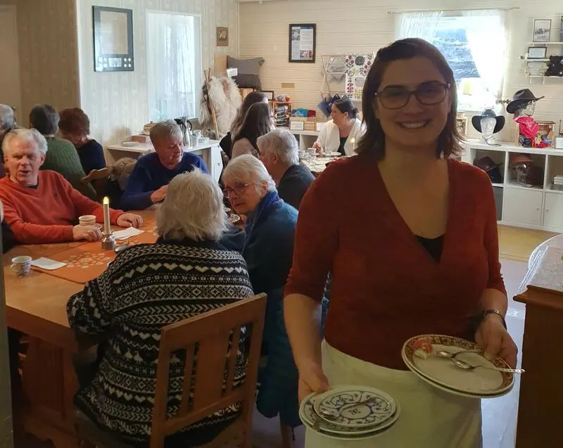 Smilende vertskap med godt humør rydder av kafebord