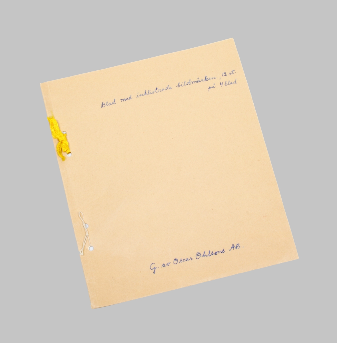 Häfte i ljusbrun papp. På omslaget skrivet i blått: "Blad med inklistrade bildmärken, 12 st på 4 blad", samt "G. av Oscar Ohlsons AB". Insidan med klistrade bildmärken i olika former och färger.