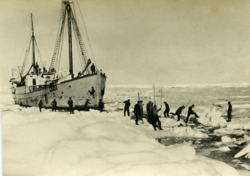 Bildet viser skute som ligger i omgitt av havis. Mange menn har hoppet ned på havisen. Skuten er ganske stor, med 2 master. Bildet er fotografert av Thorleif Bjertnes omtrent i 1933-1934.