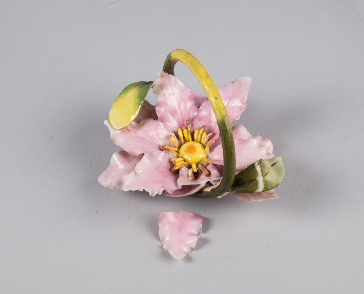Modellert blomst med lange spisse kronblader. Formet som en kurv med hank over. Til borddekor.