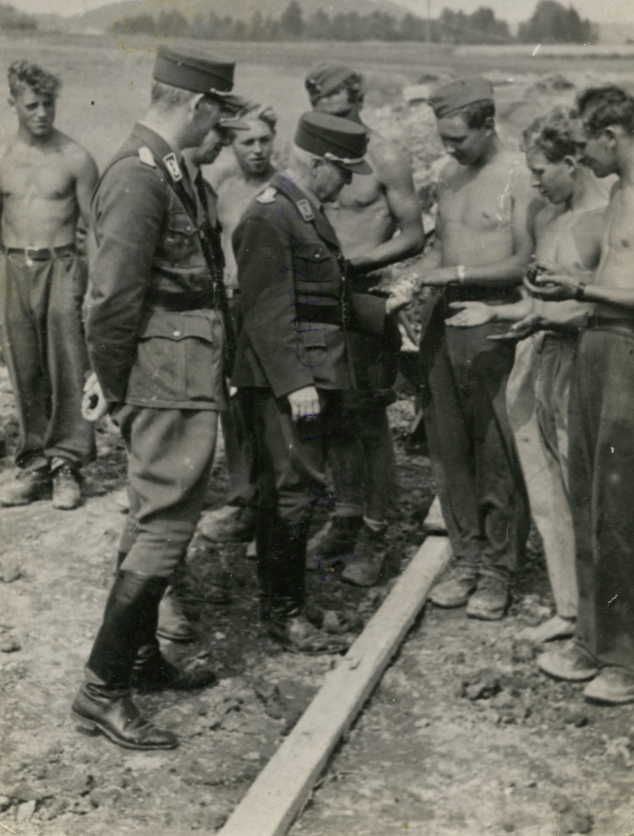 Arbeidstjeneste 2. verdenskrig.
Oberst Carl Frølich Hanssen, leder for arbeidstjenesten i Norge 1940-45. Sjekker træler i henda på Kjell Gudesen, Selbak.