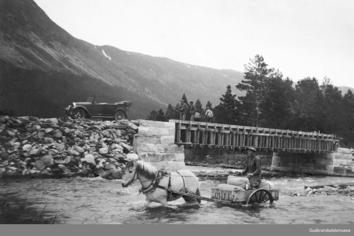 Frå bygginga av søre Åmotsbrua ca. 1936.
Olav Øiberg (f. 1895) køyrer med hest og kjerre til Åstrakverna over elva ved sida av brua