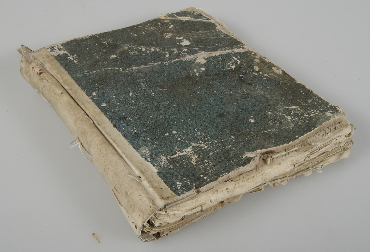 Dagbok i form av lösblad som satts ihop med tråd. Papper i blåaktig respektive gulaktig ton. Handskrivet med bläck. Pärm med blågrönt spräckligt mönster.