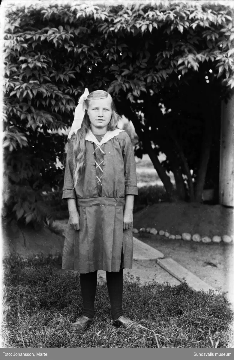 Porträttfoto av en ung flicka i en trädgård. Möjligen är det Ester Åberg, fotografens kusin.