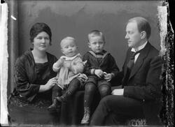 Portrett av familie på fire fotografert i studio. Kvinne og 