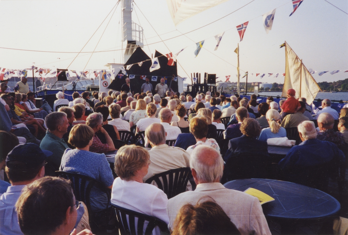 Utställningen "Människor och båtar i Norden". Tre stycken talare samt ett publikhav på däcket av fartyget M/S NORDWEST.