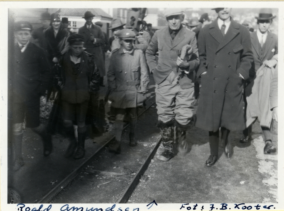 Folkegruppe på vandring langs skinnegang. Roald Amundsen i Bergen i forbindelse med "Latham-47" ekspedisjonen.