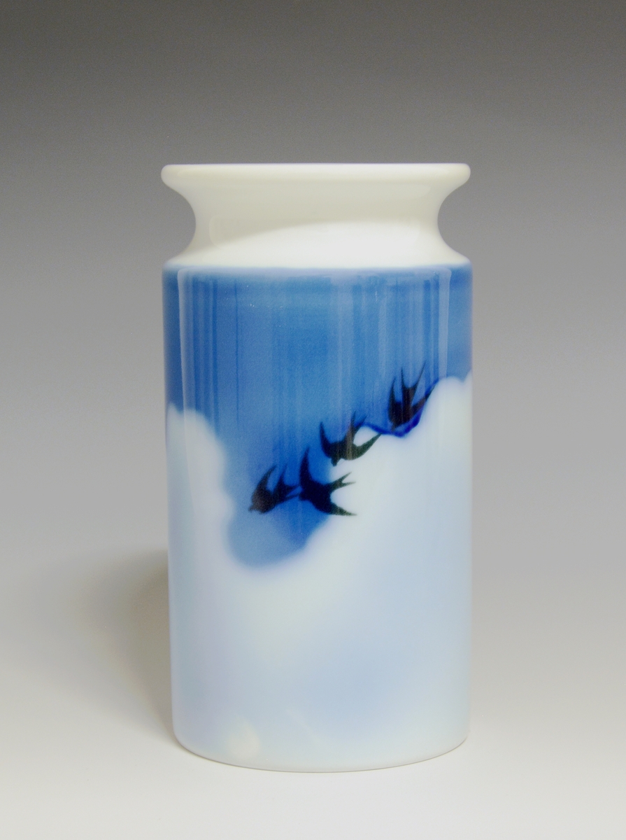 Vase i porselen. Dekorert med svaler mot skyer og blå himmel på to sider i underglasurdekor.

Kunstner: Eystein Sandnes