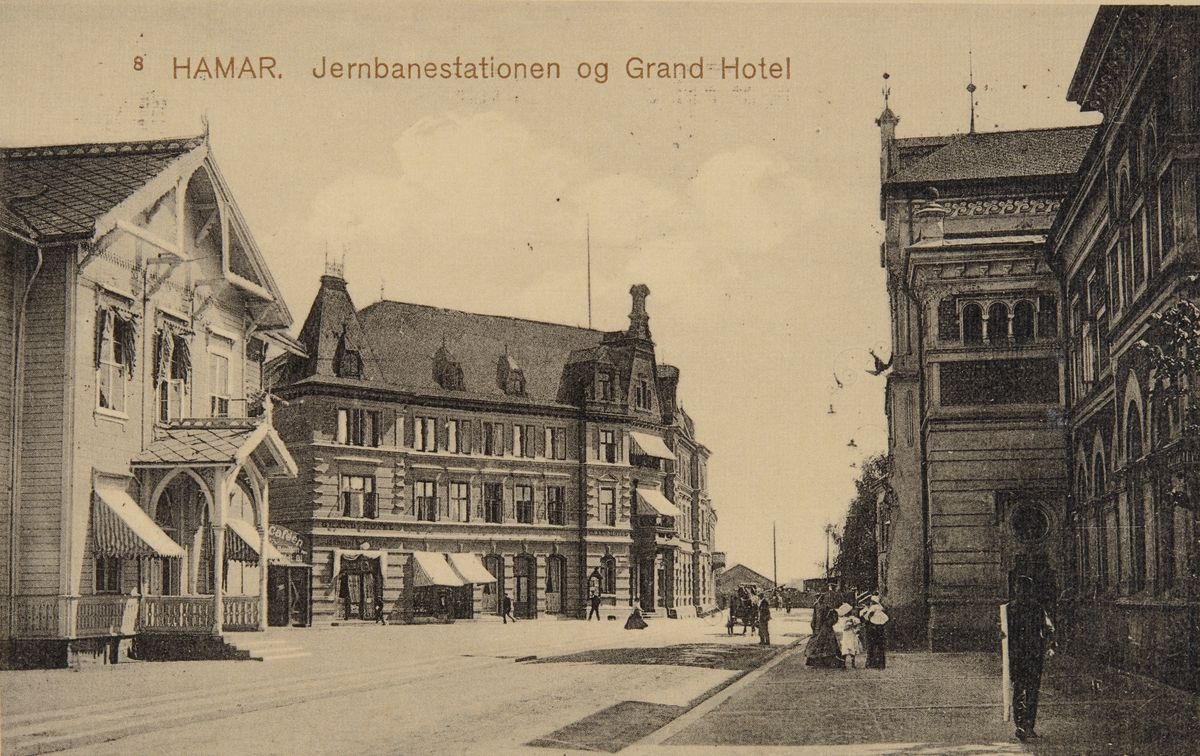 Postkort, Hamar jernbanestasjon, Jernbaneplassen med Hamars første stasjonsbygning til venstre, Grand Hotel og Hamar stasjon,