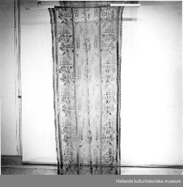 Trådgardin bestående av sex raka längder och en veckad kappa av brunbeige bomullsspets med effektinslag av silke (konst).