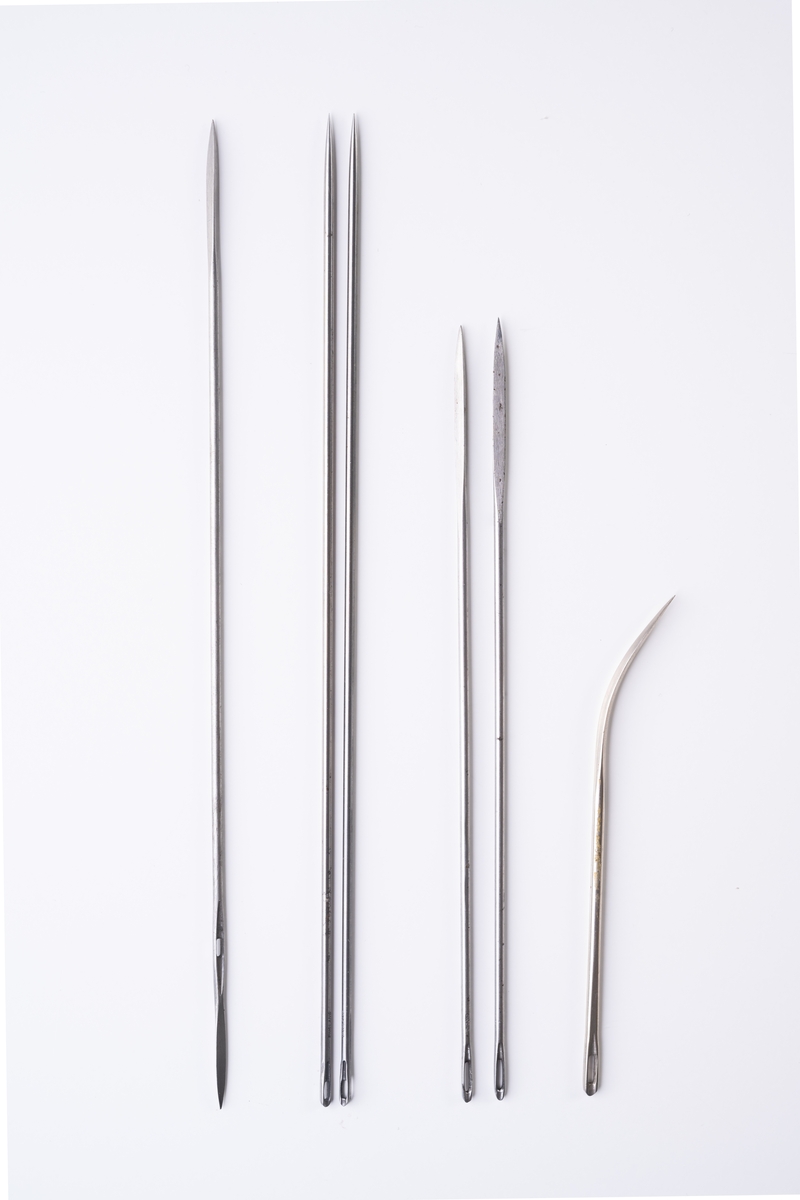 Madrassnålar, 6 st, i öppnad pappersförpackning. Förpackningen innehåller huvudsakligen långa, raka nålar av metall med olika typer av spetsar, och ovalt öga i den andra änden. En nål har tresidig spets i båda ändarna och nålsöga. Nålen är märkt: "MADE IN ENGLAND". Två nålar har konisk spets, märkta: "ENGLAND". Två nålar har tresidig spets, märkta: "ENGLAND". En nål är kortare och böjd i ena änden med fyrsidig spets.

Förpackningen består av ett beige omslagspapper och ett inre vaxat papper (trasigt). På omslagspapperet sitter en gul pappersetikett: ”SERPENT BRAND TRADE MARK ART No. C5129 MATTRESS NEEDLES STRAIGHT. OVAL EYE ONE POINT 12 Gauge 10 Inch 1 DOZEN JOHN JAMES & SONS, REDDITCH. MADE IN ENGLAND”. På papperet är stämplat: "53 665", och även handskrivet: "53".

Se vidare Historik.