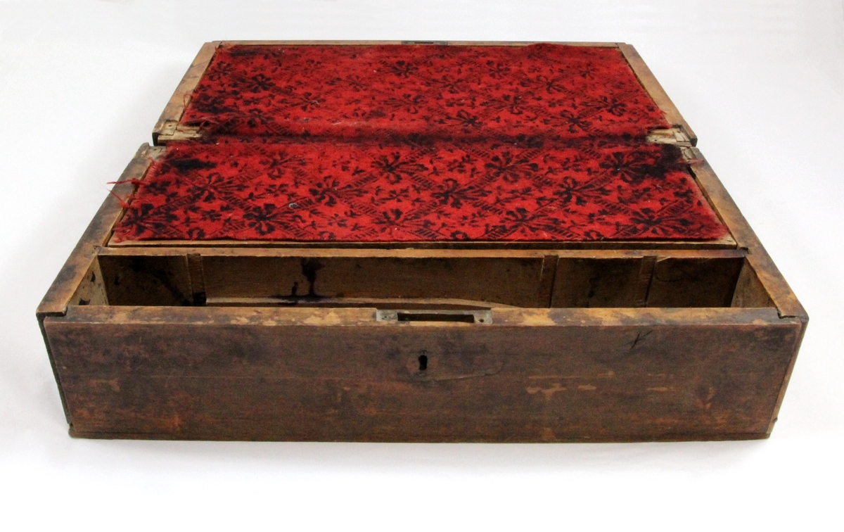 Skrivepult fra Sollia/Myrbakken i Målselv. Skrivebrettet er dekket med rød filt med trykt ornamentering/mønster i sort. Låsekasse.
