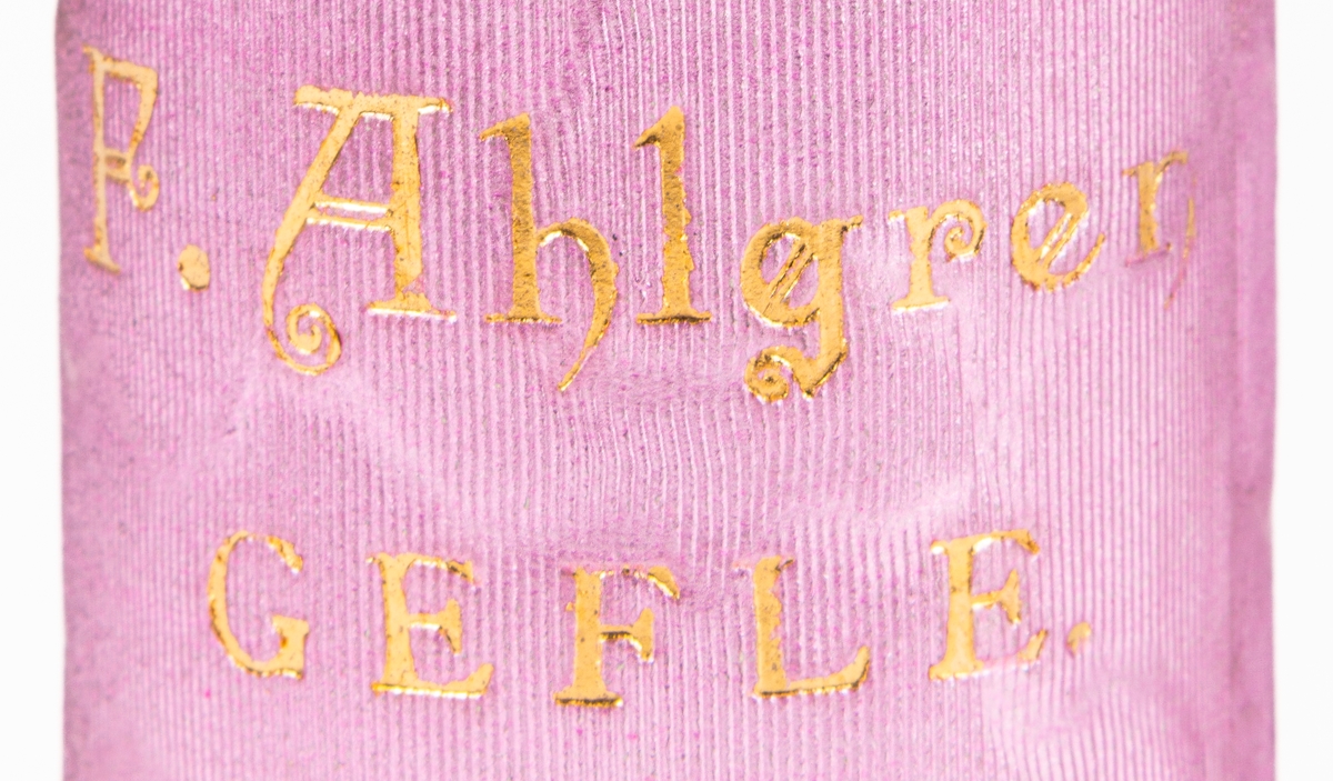 Parfymask i papp, cylinderformad, i glansigt lila papper med guldfärgad text "Parfumerie".