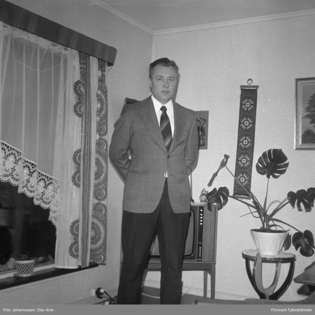 Leif Olsborg foran vindu med tidstypiske storch gardiner 

Foto trolig tatt på tidlig 1970-tallet