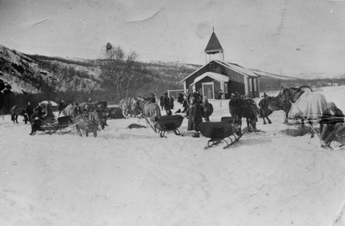 Hester med slede utenfor Polmak kirke på vinter. Det står også noen mennesker ute, noen av dem i sameklær.