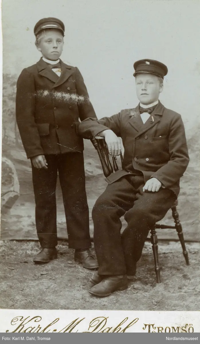 Portrett av to unge gutter. En sitter på en stol og en står ved siden. Arne Jørgenius Dahl, født i 1889 og  Johan Heyerdahl Korneliussen (1888-1904) fra Korsaksel på Engeløya.
