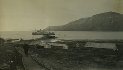 Et skip på vei til kaia i Longyearbyen. Mann går langs skinn