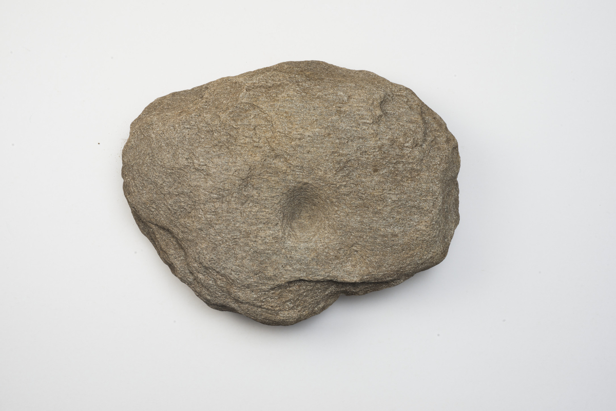 Flat, rund stein med én skålgrop. Skålgropen har en diameter på 4,5 cm. Funnet som skoningsstein i stolpehull i hus II. Mulig glimmerskifer (evnt. gneis, fyllitt)