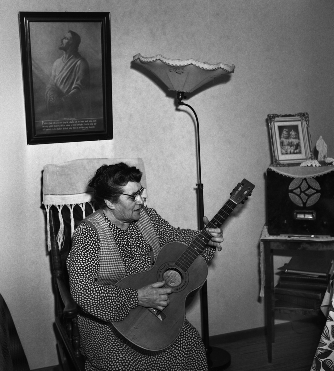 Fru Tekla Unell, 68 år gammal. Hon var glad över att få bo i Linköpings pensionärslägenheter. Hon bodde på Götgatan 11a i övre Vasastaden. Hon var änka till babtistpastorn David Uhnell. På bilden håller hon i en gitarr och sitter i en gungstol.

...
...
...

385 bilder om Linköping på 1950-talet från tidningen Östgötens arkiv. Framtidstro och optimism är ord som sammanfattar Linköping på femtiotalet. Årtiondet innebar satsningar för att förbättra linköpingsbornas livsvillkor. Bostadsfrågan och trafiklösningarna dominerade den lokalpolitiska agendan.
Bilderna digitaliserades år 2013.
