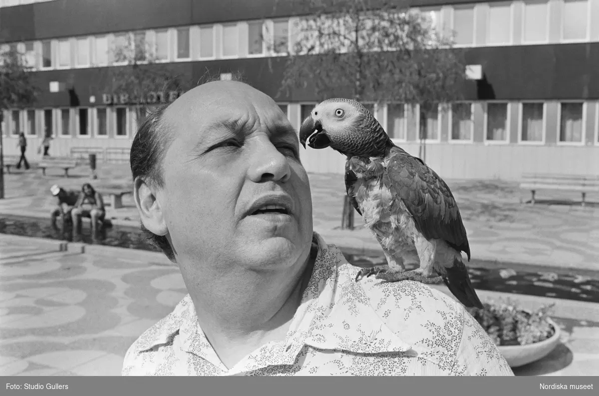 Tensta 1976. Porträtt av en man med papegoja framför Tensta bibliotek.