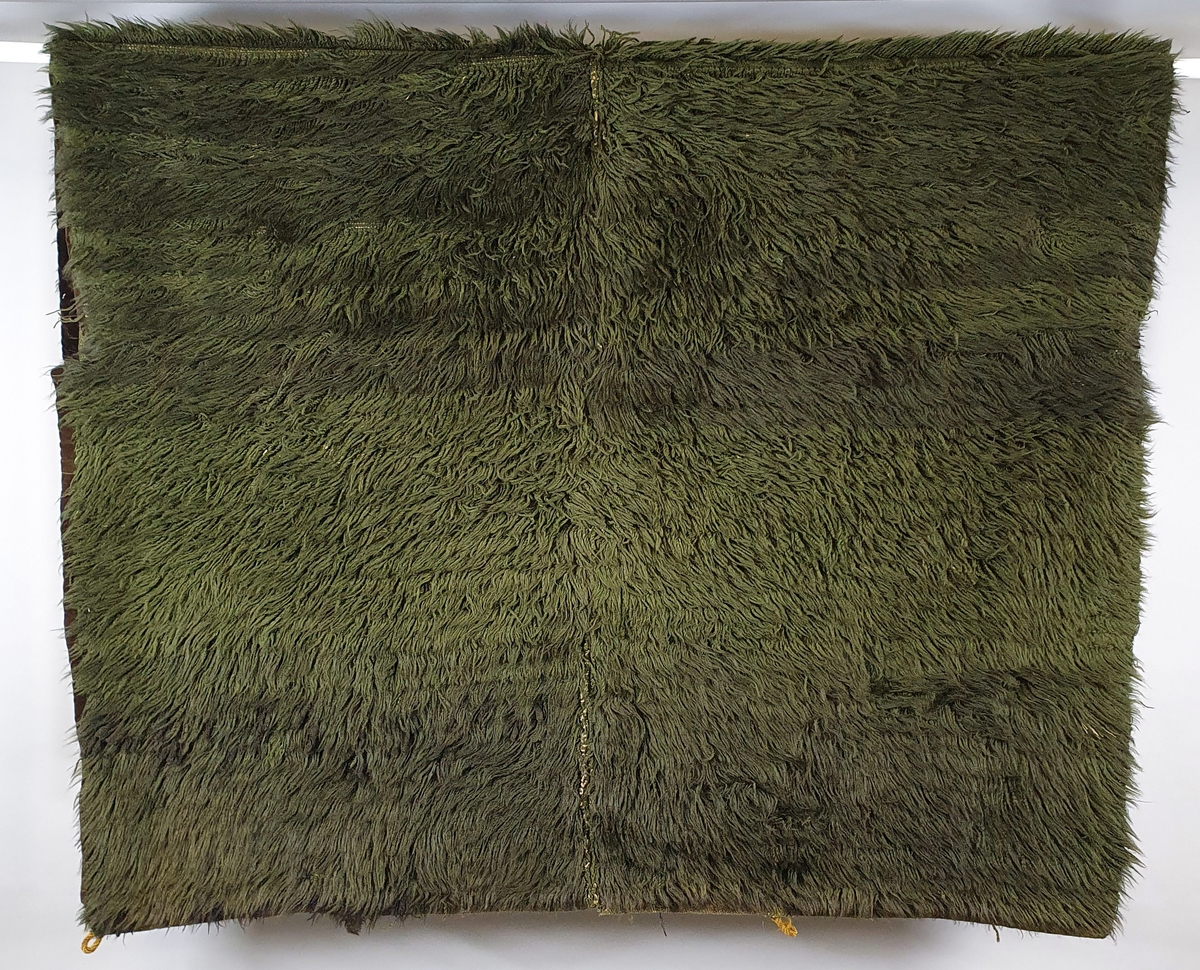Mørkegrønt knytteteppe, satt sammen av fire deler. Kantbånd av mørkebrun fløyel på 1 eller 2 sider av hver del. Renning av lin med innslag og knuter av ull.